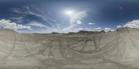 a large sand desert with blue skies and the sun in the sky and clouds above