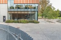 someone has fallen down to his skateboard in a courtyard of a building with bushes and trees