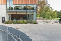 someone has fallen down to his skateboard in a courtyard of a building with bushes and trees