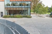 someone has fallen down to his skateboard in a courtyard of a building with bushes and trees