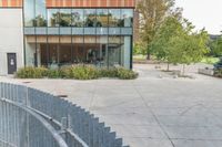 someone has fallen down to his skateboard in a courtyard of a building with bushes and trees