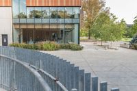 someone has fallen down to his skateboard in a courtyard of a building with bushes and trees