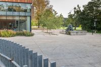 someone has fallen down to his skateboard in a courtyard of a building with bushes and trees