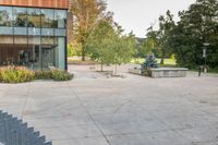 someone has fallen down to his skateboard in a courtyard of a building with bushes and trees