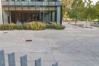 someone has fallen down to his skateboard in a courtyard of a building with bushes and trees