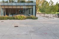 someone has fallen down to his skateboard in a courtyard of a building with bushes and trees