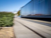 a train travels along a track with trees behind it with motion blurers from moving objects