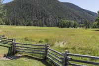 this is the fence that separates two pasture areas of land next to mountains and a meadow