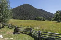 this is the fence that separates two pasture areas of land next to mountains and a meadow