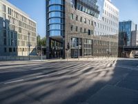 city street with an empty street with cars driving past it and a large glass building in the background