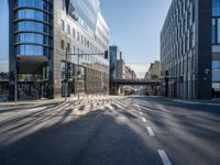 this empty street has buildings and traffic lights on it's sides in the sunshine