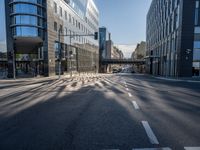 this empty street has buildings and traffic lights on it's sides in the sunshine