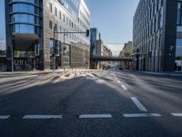 this empty street has buildings and traffic lights on it's sides in the sunshine