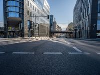 this empty street has buildings and traffic lights on it's sides in the sunshine