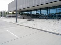 a white parking lot with an empty bench sitting on top of it and a large building behind it