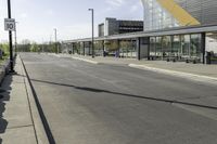 a street corner with an empty street and a bus parked nearby on the road side