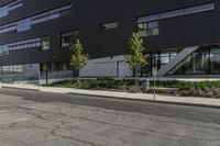 a parking lot next to a tall black building and some trees on it's side