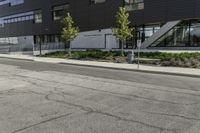 a parking lot next to a tall black building and some trees on it's side