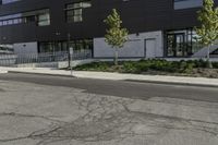 a parking lot next to a tall black building and some trees on it's side