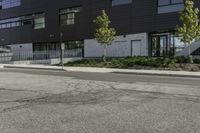 a parking lot next to a tall black building and some trees on it's side