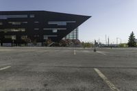 a black building with an orange sign sitting on top of a parking lot with lots of trees in front