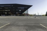 a black building with an orange sign sitting on top of a parking lot with lots of trees in front