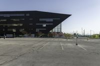 a black building with an orange sign sitting on top of a parking lot with lots of trees in front