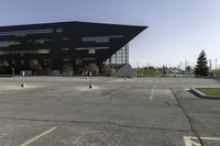 a black building with an orange sign sitting on top of a parking lot with lots of trees in front