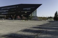 a black building with an orange sign sitting on top of a parking lot with lots of trees in front