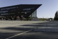 a black building with an orange sign sitting on top of a parking lot with lots of trees in front