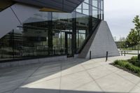 a large building with a window on the side of it on a concrete sidewalk in front of an empty grassy area