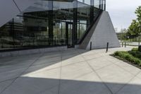 a large building with a window on the side of it on a concrete sidewalk in front of an empty grassy area