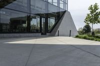 a large building with a window on the side of it on a concrete sidewalk in front of an empty grassy area