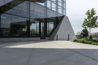 a large building with a window on the side of it on a concrete sidewalk in front of an empty grassy area