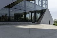 a large building with a window on the side of it on a concrete sidewalk in front of an empty grassy area