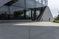 a large building with a window on the side of it on a concrete sidewalk in front of an empty grassy area