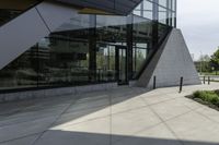 a large building with a window on the side of it on a concrete sidewalk in front of an empty grassy area