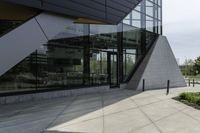 a large building with a window on the side of it on a concrete sidewalk in front of an empty grassy area