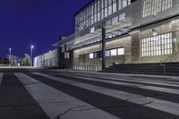 the empty street has stairs and windows on it at night outside a building or convention center