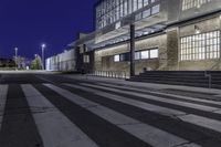 the empty street has stairs and windows on it at night outside a building or convention center