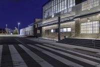 the empty street has stairs and windows on it at night outside a building or convention center