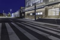 the empty street has stairs and windows on it at night outside a building or convention center