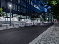 benches and street lighting in front of a building at night in an urban setting -