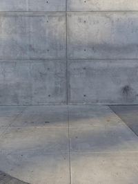 a fire hydrant stands outside of a large gray wall on the side of a street