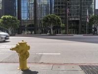 a yellow fire hydrant sitting on the side of a street near tall buildings and cars