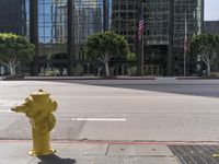 a yellow fire hydrant sitting on the side of a street near tall buildings and cars