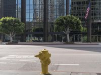 a yellow fire hydrant sitting on the side of a street near tall buildings and cars