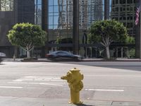 a yellow fire hydrant sitting on the side of a street near tall buildings and cars