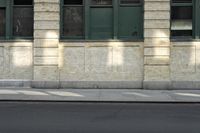 a fire hydrant on a street near a brick building with green doors and windows