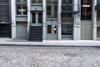 a fire hydrant sitting outside of a glass building with stairs next to it and a parking meter in front